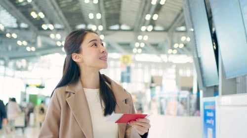 Asian young woman passenger checking depature boarding pass in airport.