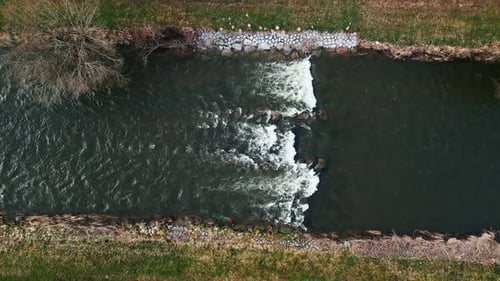 Top drone view of clear transparent water fast streaming through stones in river
