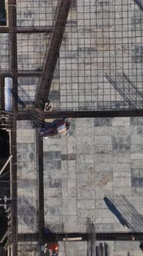 Vertical Video Aerial Perspective of Workers on a Construction Site Preparing New Structures and