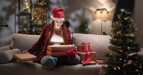 Woman in Santa Hat Opening Christmas Present