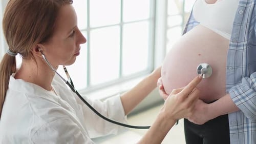 врач слушает сердце беременной женщины стетоскопом
