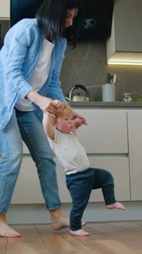 Mother Helps the Baby Boy Learn to Walk Child Learns to Take the First Steps Holding His Mother's