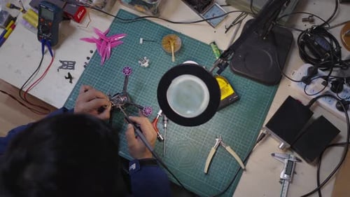 Personne travaillant sur un petit appareil électronique effectuant des réparations détaillées et un assemblage à l'aide d'une soudure