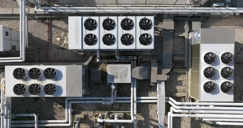 Industrial building rooftops with vents and pipes lined across, Top down view