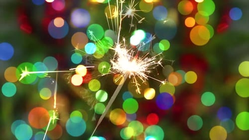 Sparkler Emits Sparks with Christmas Lights Bokeh