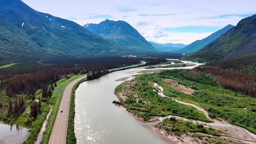 Flight over the river flowing in the picturesque valley among the mountains.