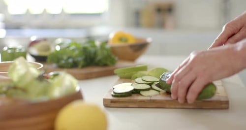 Slicing Fresh Cucumber on Wooden Cutting Board