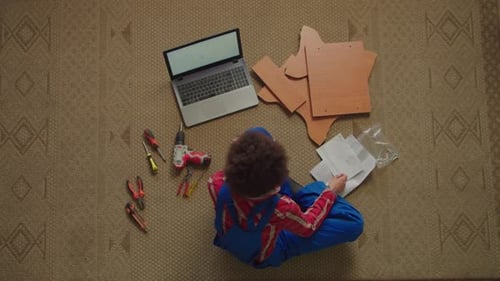 Overhead View of Black Female Watching Tutorial Video to Assemble DIY Furniture