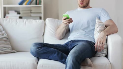 Man Using Smartphone on Couch in Living Room