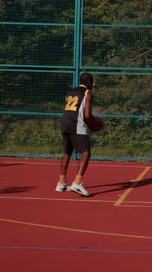 Ein Basketballspieler wird auf einem Außenplatz in Aktion gesehen, der beeindruckende Fähigkeiten und Agilität unter Beweis stellt