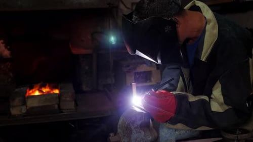 A Handyman Performs Welding and Grinding at His Workplace in the Workshop