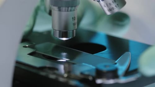 Unrecognizable Scientist Placing Glass Slide on Microscope