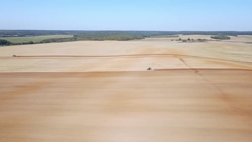 An aerial view of a tractor working on a large agricultural field.