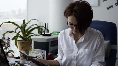 Businesswoman Checking Receipts and Smiling in Office
