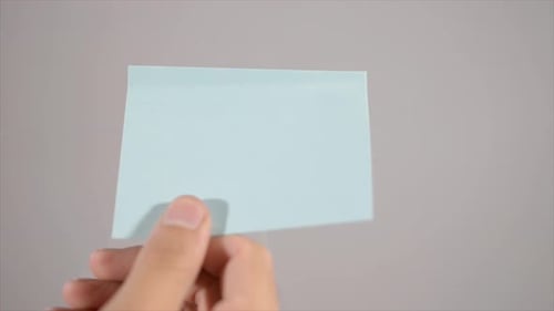 Hand Placing Blue Square Paper on Background