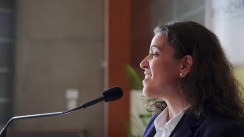 Woman Speaks at Podium Using Microphone Indoors