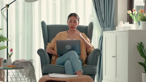 Woman Works on Laptop in Armchair at Home