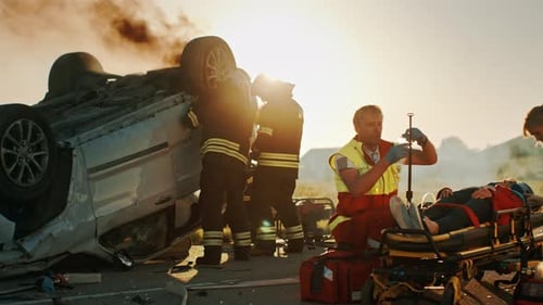 Paramedics tending to patient after car crash at sunset