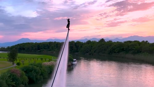 Aerial View Bold Girl Flyboarding Across River at Sunset
