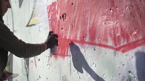 Junger Mann malt Graffiti an die Wand.
Zeitlupe
