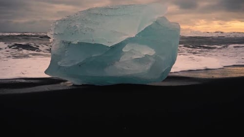 Slow motion shots of blue icebergs on Diamond beach in Iceland. Black sand beach at sunset. Differen