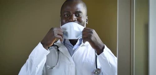 Doctor in Lab Coat Removes Face Mask and Smiles