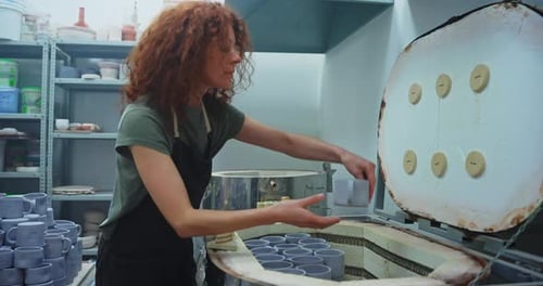Woman Examining a Ceramic Mug in a Pottery Studio