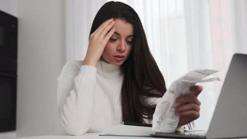 Mulher chateada analisa o valor gasto em cheque após fazer compras