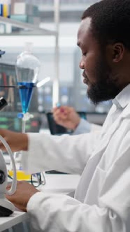Scientist Using Microscope in Laboratory with Test Tubes