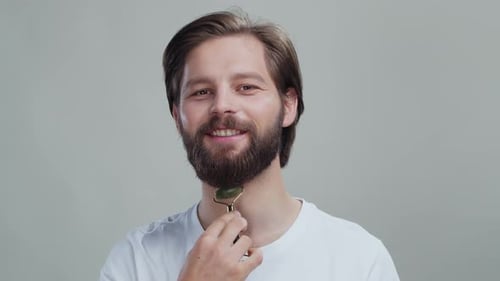 Bearded Man using a jade facial roller