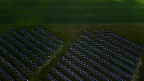 An Aerial View Captures Solar Panels in Green Fields Producing Renewable Energy in a Scenic