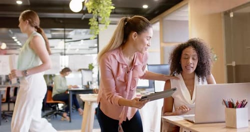 Femmes d'affaires heureuses et diverses discutant du travail et utilisant une tablette au bureau, au bureau, au ralenti