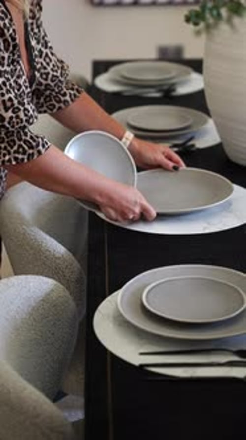 Woman sets modern dinner table at home
