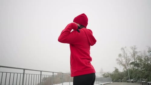 Side View of Woman Performing Hand Stretch Outdoors in Winter Fitness Routine