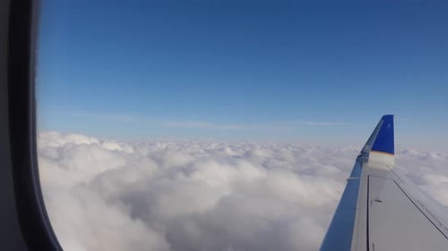Flugzeug fliegt durch weiße Wolken und blauen Himmel