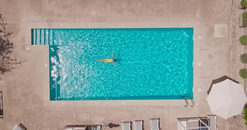 Top Down View of a Woman in an Yellow Swimsuit Lying on Her Back in the Pool