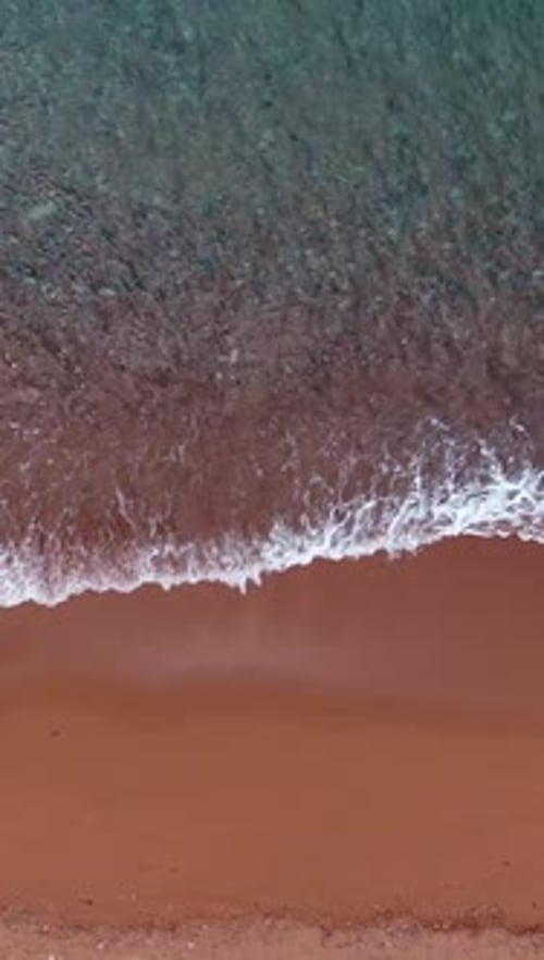 Splashing Sea Waves and Clean Water Near Red Sandy Beach Aerial View Vertical Video