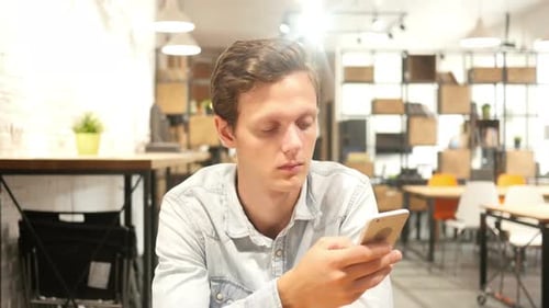 Young Man Typing Message on Smartphone