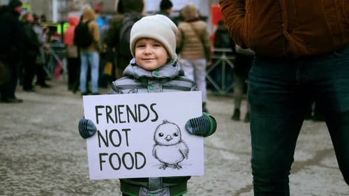 Un petit garçon tient une bannière végétalienne lors de la manifestation pour les droits des animaux