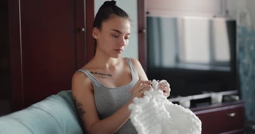 Young Woman Crocheting on Couch at Home