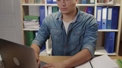 Captura con zoom de un joven empleado que usa el teclado de una computadora portátil mirando a la cámara