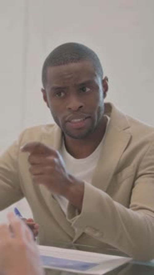 Man in Blazer Discusses Documents in Meeting