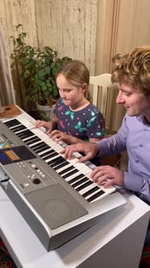 Child and Adult Playing an Electronic Piano Indoors