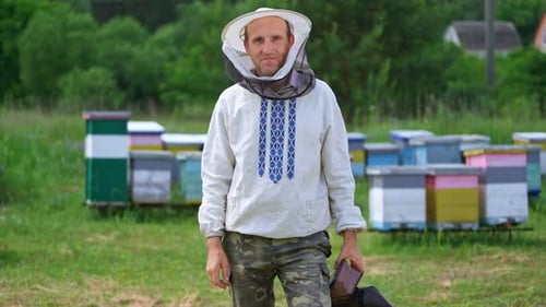 Portrait of beekeeper man. Apiarist in white shirt and protective hat holding chimney with smoke