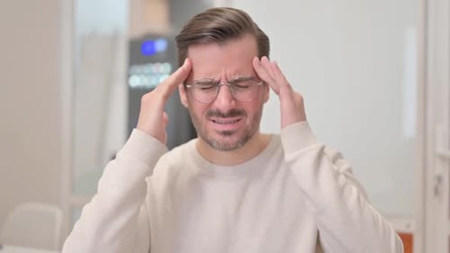 Portrait of Young Man with Headache in Office