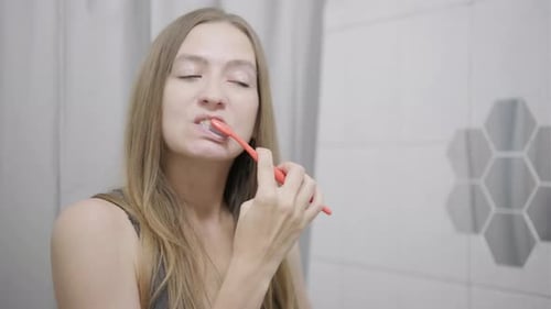 Woman Brushing Teeth in Bright Bathroom