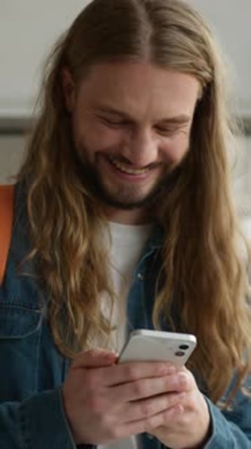 Kaukasischer Mann lacht humorvoll, freudig, lustig, hält Handy, Smartphone, Technologie, Typ, männlich