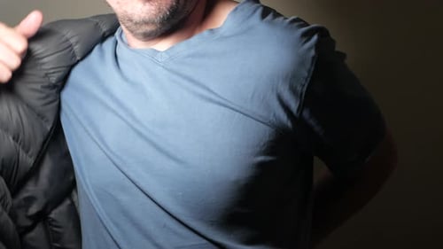 Man Putting on Gray Winter Jacket Indoors