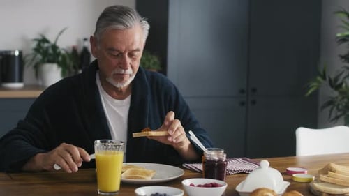 Senior caucasian man eating breakfast at home. Shot with RED helium camera in 8K.