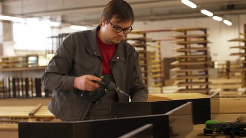 Man Drilling Wood in Workshop with Power Tool